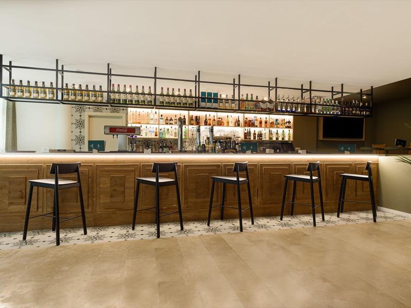 Bar moderno con sgabelli in legno e mensola luminosa sospesa.