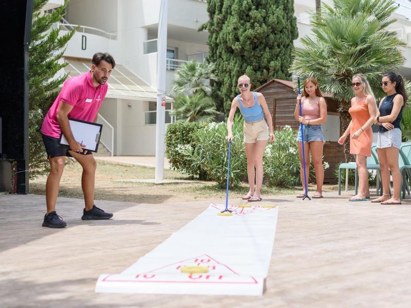 Un uomo gioca a shuffleboard con un gruppo di donne all'esterno dell'hotel.