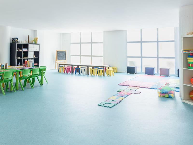 Sala luminosa con sedie colorate e area giochi per bambini.