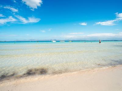 Clear, shallow water at a white sandy beach under a blue sky with few clouds.