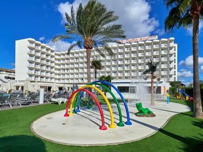 Modern hotel with pool playground and six colorful rainbow arches in front of the building under a blue sky.