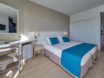 Elegant hotel room with double bed, blue accents, and desk by the window.