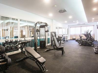 Palestra luminosa con vari attrezzi per allenamento e pesi su pavimento scuro.