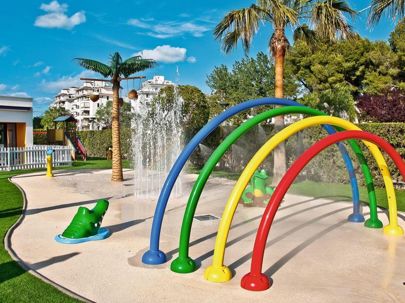 Colorful water playground with rainbow arches and water fountain outdoors under blue sky.