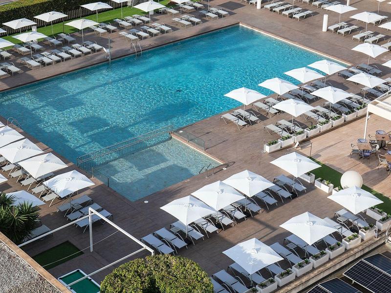 Modern outdoor pool with sun loungers and umbrellas at a hotel resort