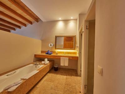 Salle de bain moderne avec plafond en bois, baignoire et miroir éclairé.