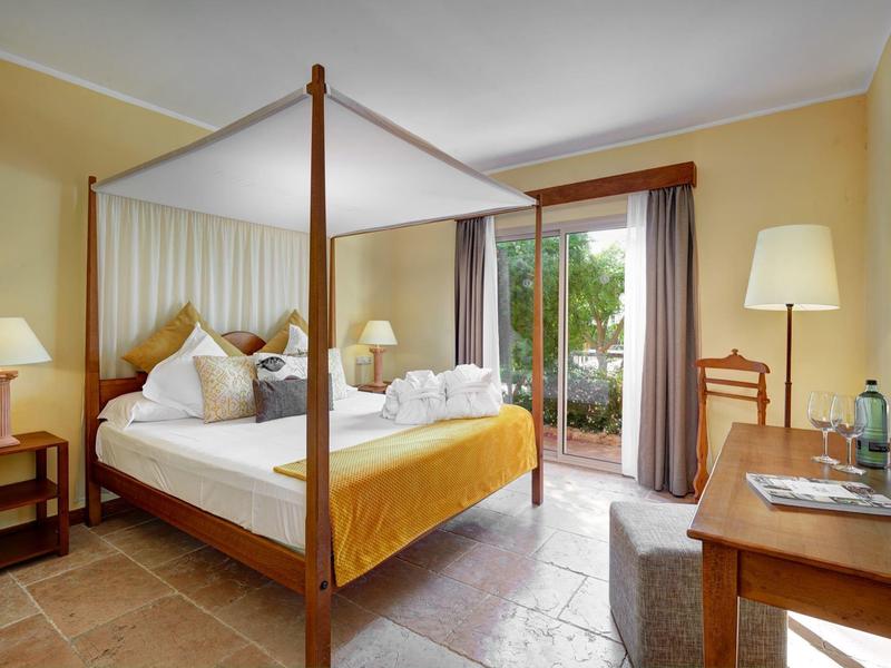 Chambre confortable avec lit à baldaquin et vue sur la terrasse.