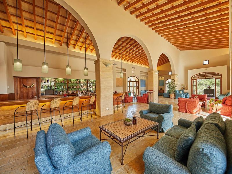 Grand salon avec groupes de sièges, comptoir de bar et hauts plafonds en bois.