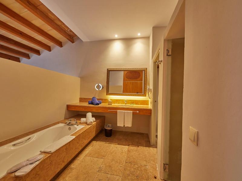 Salle de bain moderne avec plafond en bois, baignoire et miroir éclairé.
