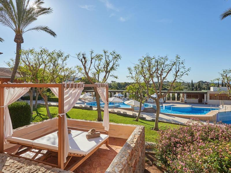 Lits lounge en plein air avec vue sur une piscine dans un hôtel tropical.