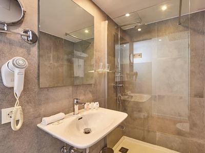 Modern bathroom with shower, sink, and hairdryer in a hotel.