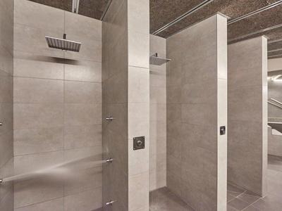 Modern shower with rain showerhead and light tiles in a hotel bathroom.