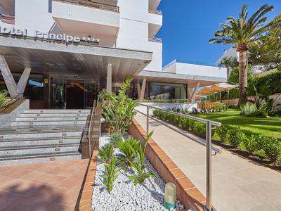 Modern hotel entrance with steps, plants, and clear blue sky.
