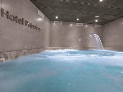 Modern indoor hot tub with waterfall feature in hotel spa area