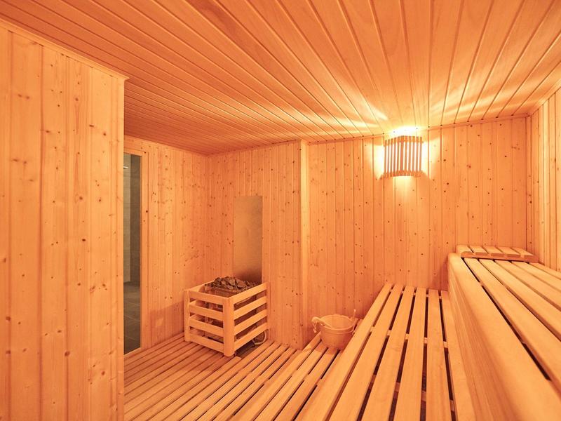 Sauna room with wooden walls, benches, and a wooden heater with hot stones.