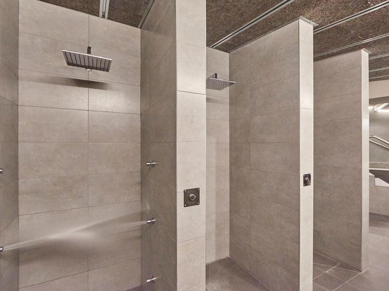 Modern shower with rain showerhead and light tiles in a hotel bathroom.