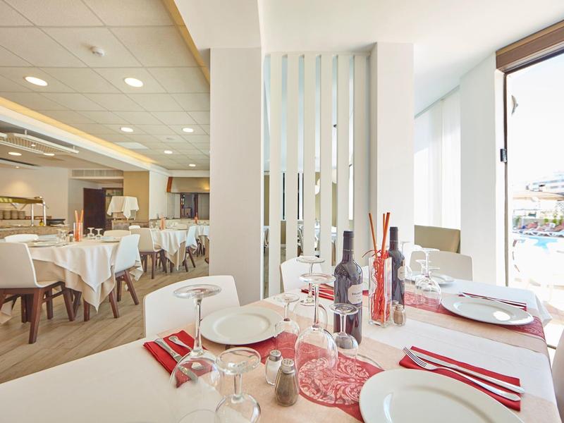 Modern restaurant with set tables and large glass front overlooking outside.