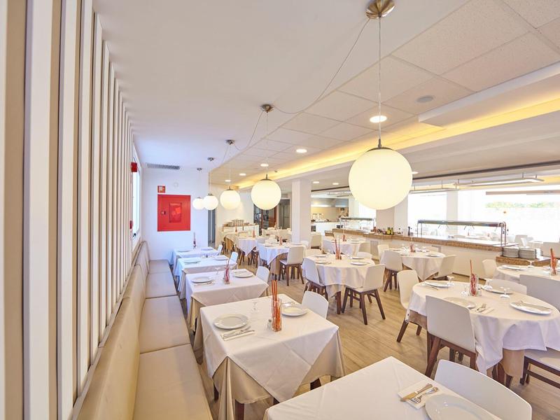 Bright, modern restaurant with white tables, chairs, and large hanging lamps.