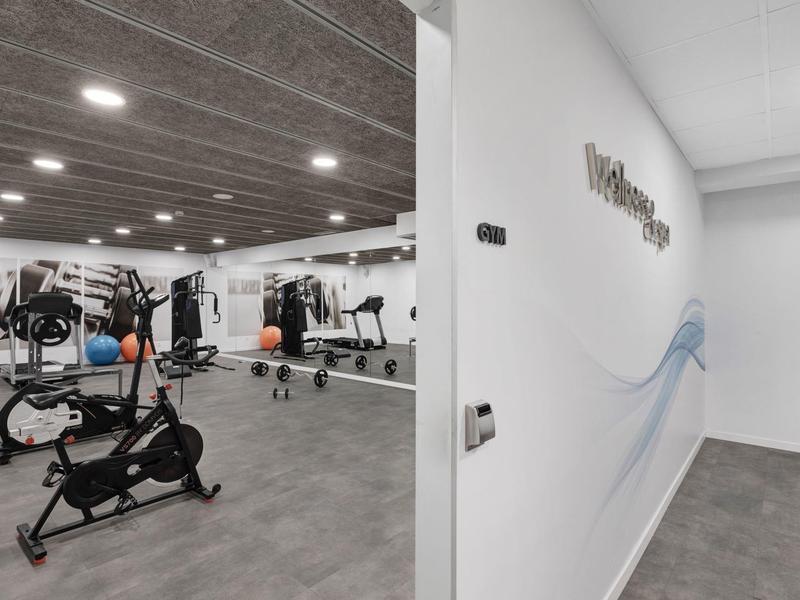 Modern fitness room with equipment like exercise bikes and dumbbells in a hotel.