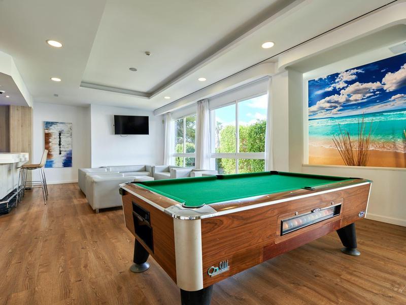 Nowoczesny pokój z stołem bilardowym, dużymi oknami i jasnym naturalnym światłem.