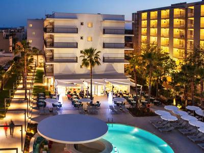 Oświetlony hotel z basenem i miejscem do siedzenia o zmierzchu