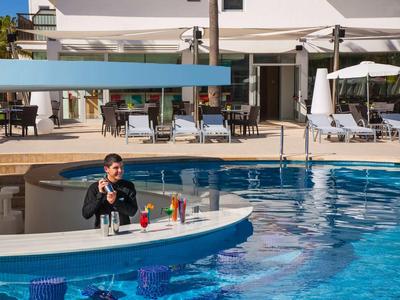 Mężczyzna przy barze basenowym z koktajlami na terenie basenu hotelowego na wakacjach.