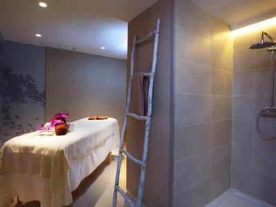 Pokój zabiegowy z łóżkiem do masażu i prysznicem, ciepłe oświetlenie i relaksująca atmosfera