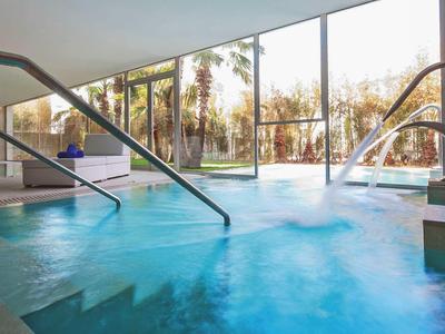 Nowoczesny basen kryty i jacuzzi z dużymi oknami z widokiem na palmy.