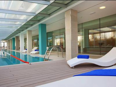 Nowoczesny kryty basen z leżakami i szklanymi ścianami w hotelu.