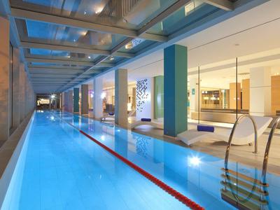 Basen kryty z gładką wodą, nowoczesnymi kolumnami i dużymi oknami.