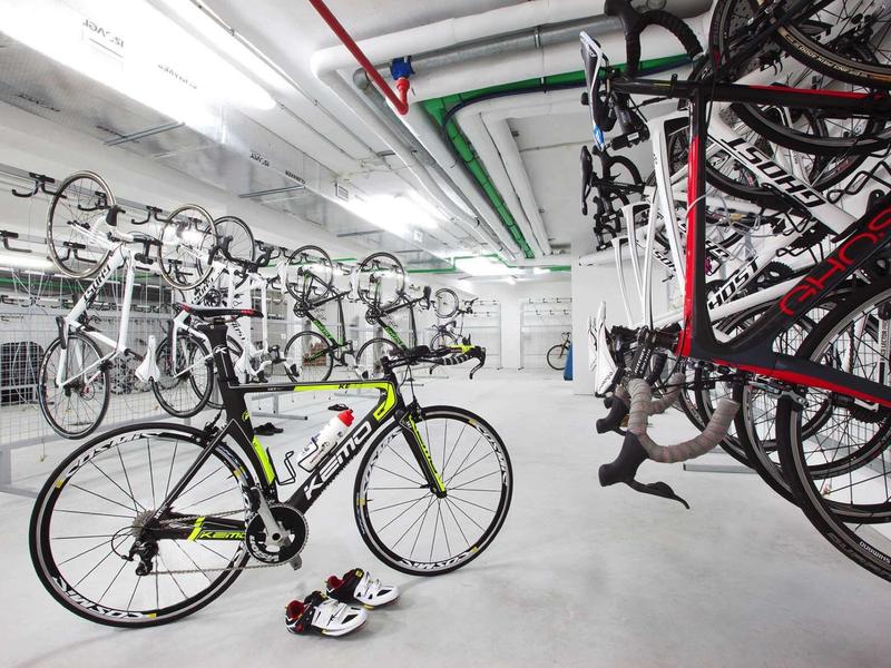 Nowoczesne pomieszczenie na rowery z rowerami szosowymi i kaskami w jasnej piwnicy.