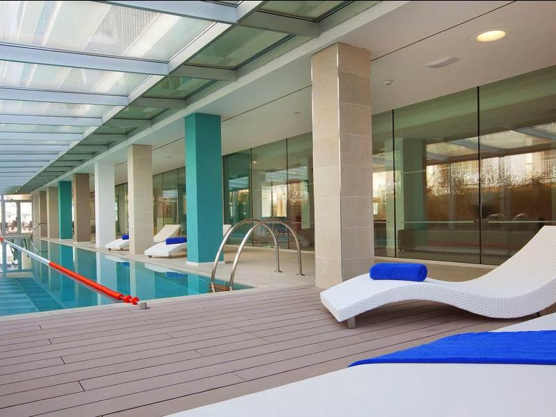 Nowoczesny kryty basen z leżakami i szklanymi ścianami w hotelu.