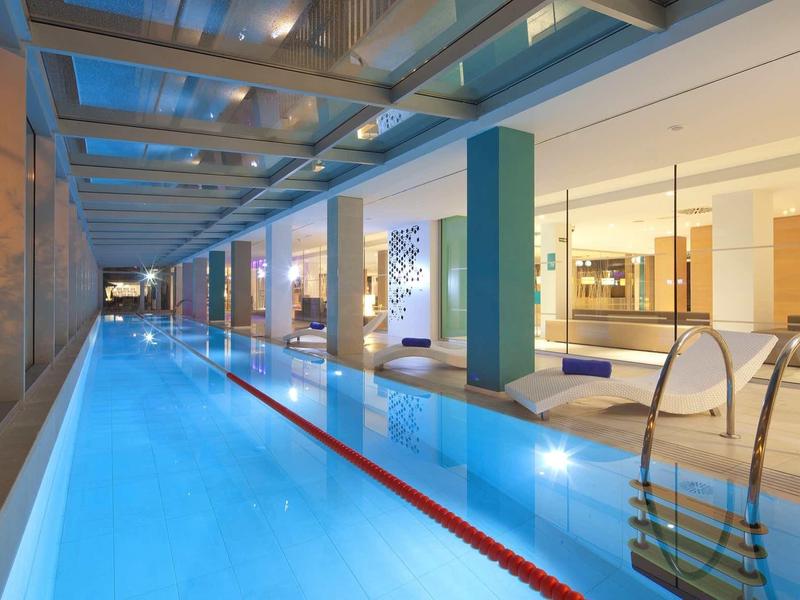 Basen kryty z gładką wodą, nowoczesnymi kolumnami i dużymi oknami.