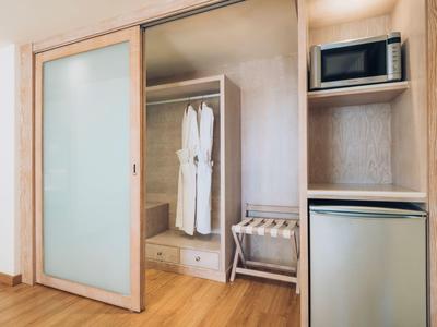 Moderner Hotelzimmer-Eingangsbereich mit offenem Kleiderschrank, Mini-Kühlschrank und Mikrowelle.