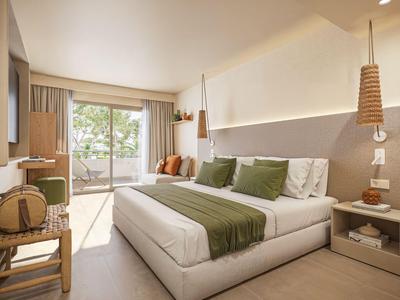 Helles, modernes Hotelzimmer mit großem Bett, grünen Akzenten und Balkon mit Blick auf Natur.