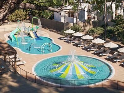 Zwei verschiedene Schwimmbecken mit Wasserspielen neben Liegestühlen und Sonnenschirmen in einer Hotelanlage.