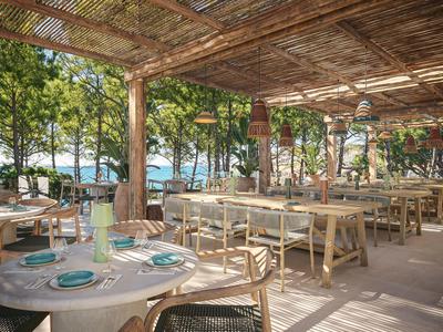 Überdachter Außenbereich eines Restaurants mit Holztischen und Blick auf das Meer.