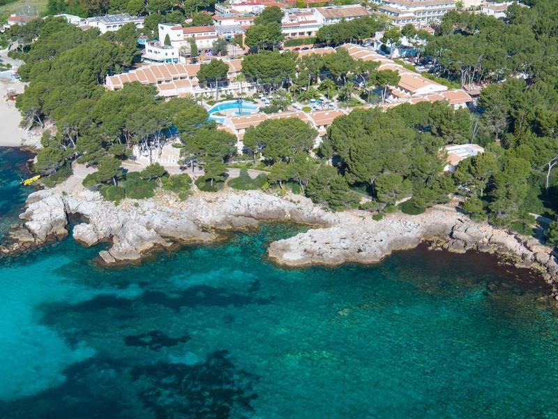 Luksusowy hotel położony w zalesionym krajobrazie nadmorskim z przejrzystą niebieską wodą.