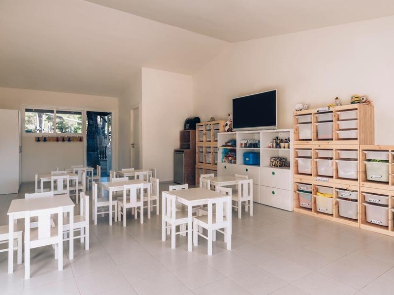 Jasne pomieszczenie z białymi stolikami i półkami dla dzieci