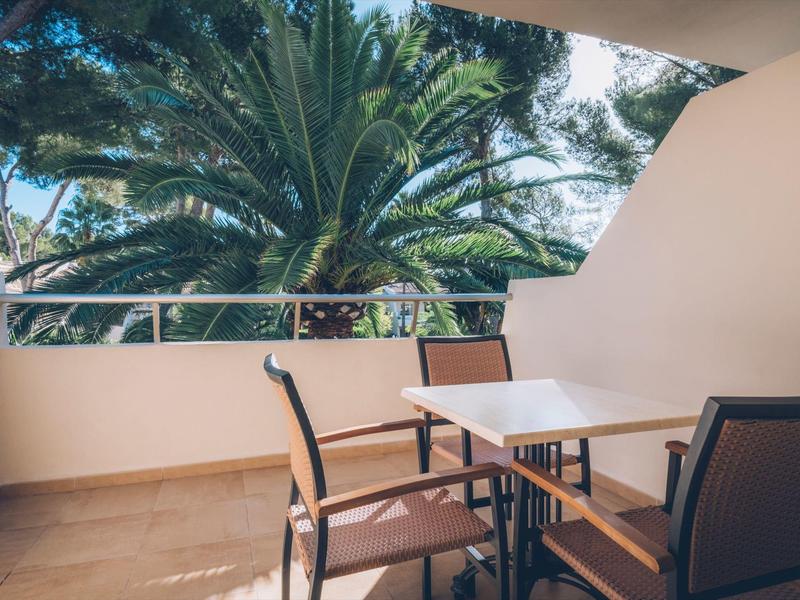 Miejsce do siedzenia z stołem i krzesłami na balkonie z widokiem na palmy.
