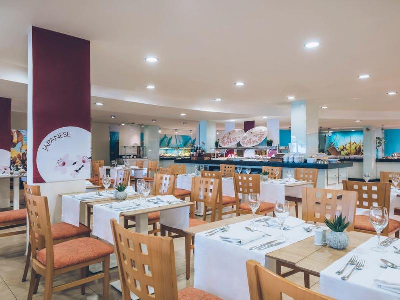 Jasna, nowoczesna jadalnia z nakrytymi stołami i drewnianymi krzesłami w hotelu.