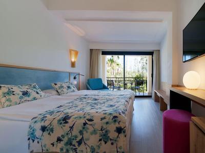 Camera d'hotel luminosa con letto matrimoniale, balcone e mobili moderni.