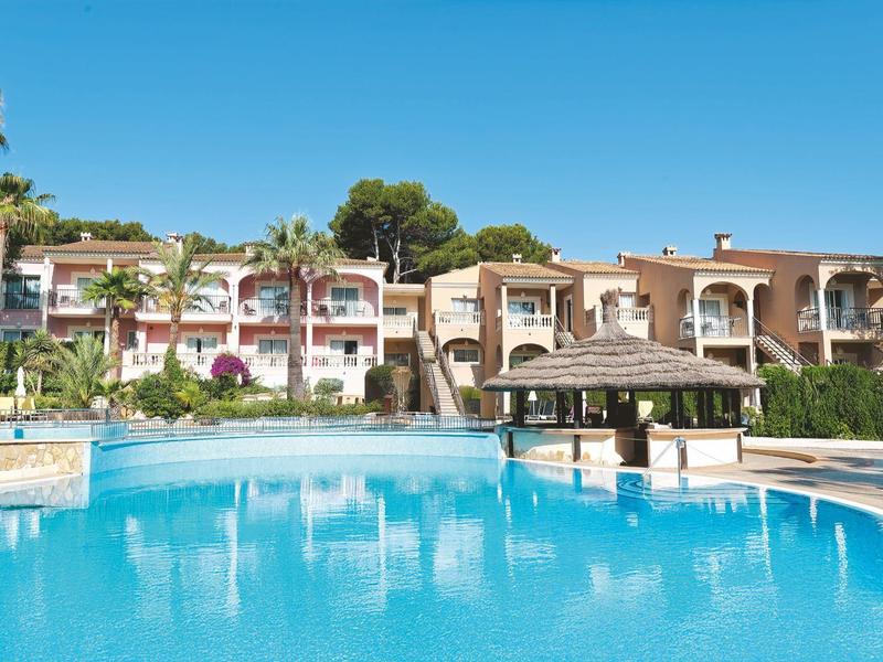 Grande piscina blu con edifici dell'hotel e palme sullo sfondo sotto un cielo sereno.