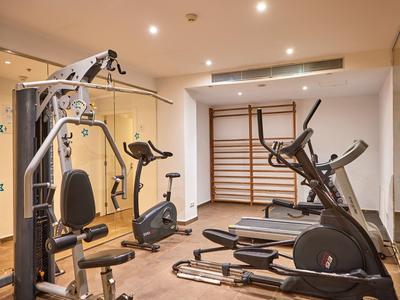 Moderní posilovna s různými cvičebními přístroji v světlé místnosti.