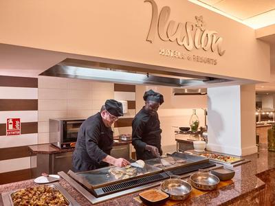 Chefs preparing food at a counter in a hotel restaurant named Nexum.