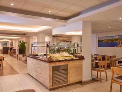 Bright, modern buffet restaurant with wooden chairs and a central food station.