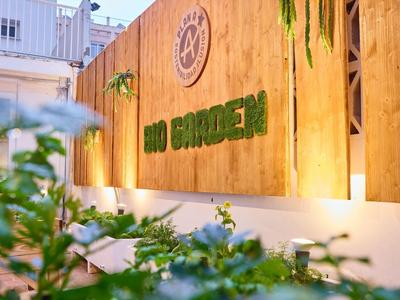Illuminated wooden sign reading 'BBQ GARDEN' with green decoration on an exterior wall.