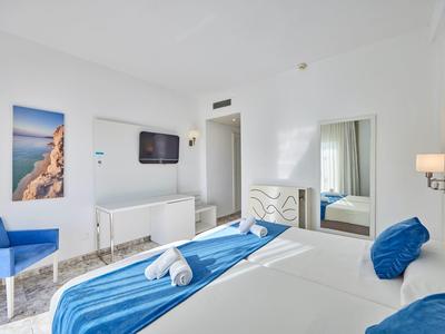 Bright hotel room with blue and white decor and double bed with towels.