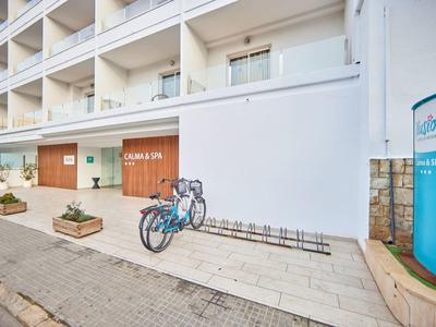 Exterior view of a modern hotel with bicycles and planters on the sidewalk.