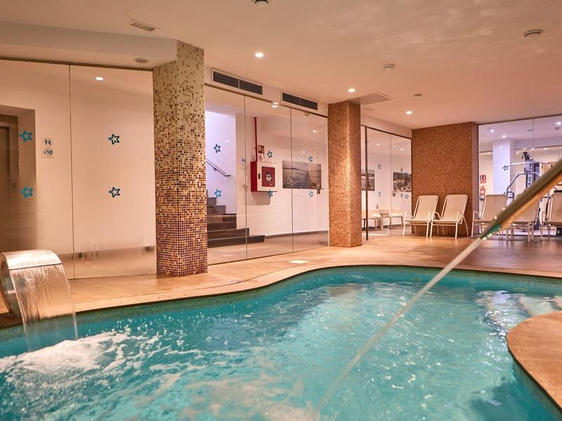 Indoor pool with water jets, seating area, and warm inviting lighting in a hotel.